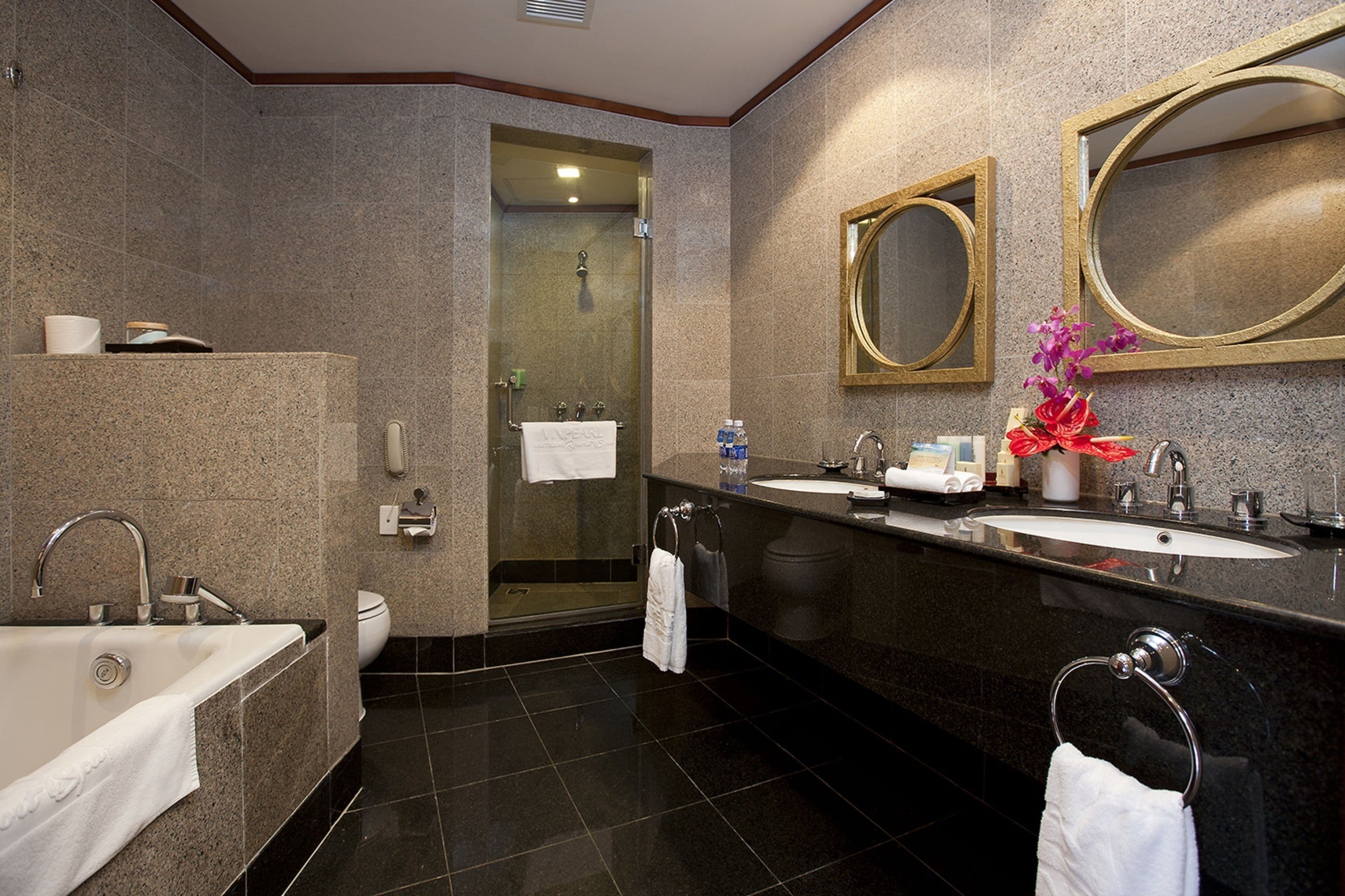 A modern bathroom with a bathtub, two sinks, a shower, and a toilet.