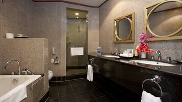A modern bathroom with a bathtub, two sinks, a shower, and a toilet.