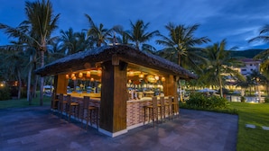 A bar area with a thatched roof, brick walls, and wooden bar stools. - Vinpearl Resort Nha Trang  (Nha Trang)