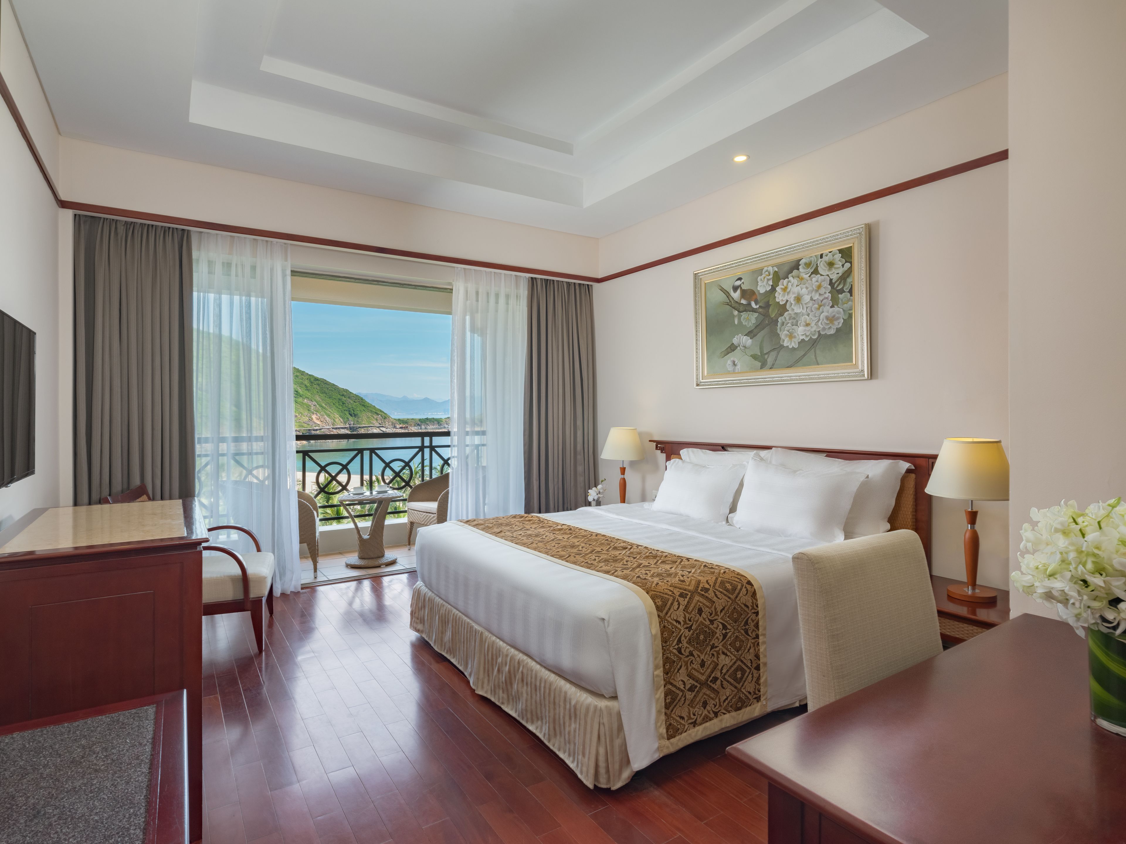 Una habitación de hotel con una cama grande, un escritorio y vista al mar.