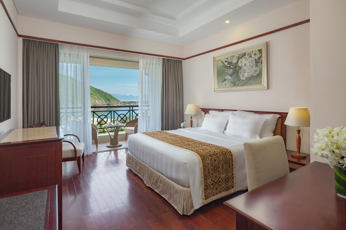 Una habitación de hotel con una cama grande, un escritorio y vista al mar.
