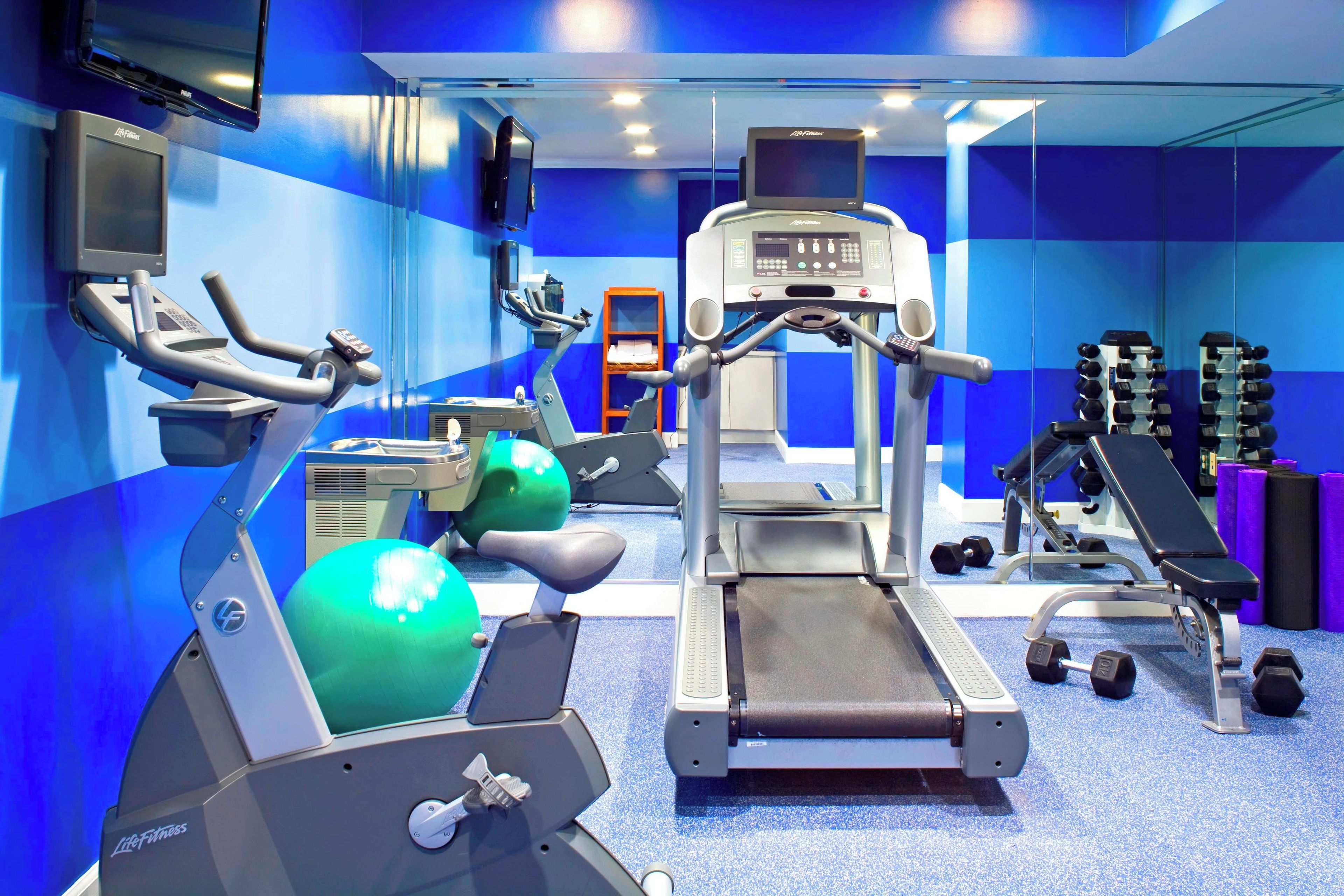 A gym with cardio equipment, weight machines, and dumbbells.