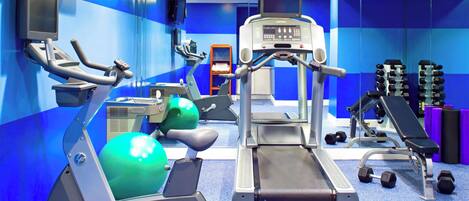 A gym with cardio equipment, weight machines, and dumbbells.