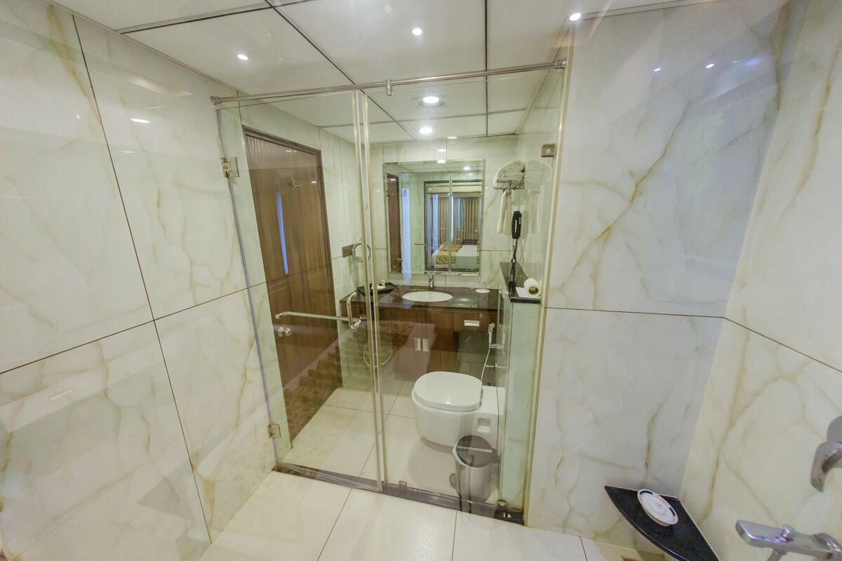 A modern bathroom with a glass-enclosed shower, a toilet, and a sink.