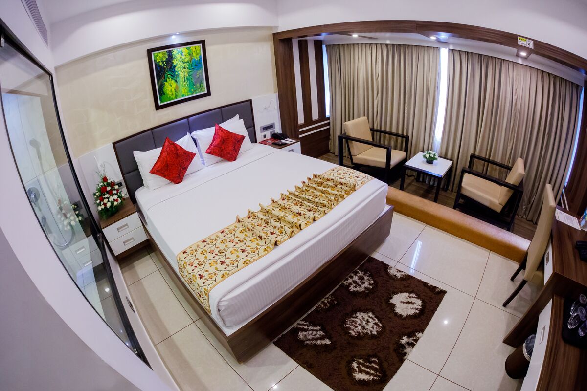 Une chambre d’hôtel avec un grand lit, un bureau, une chaise, une petite table et un rideau.
