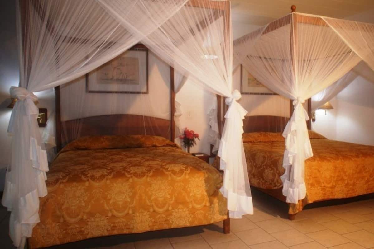 Two double beds with canopy beds, wooden headboards, and a framed picture on the wall.