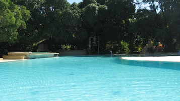 Una piscina al aire libre, sombrillas, sillones reclinables de piscina