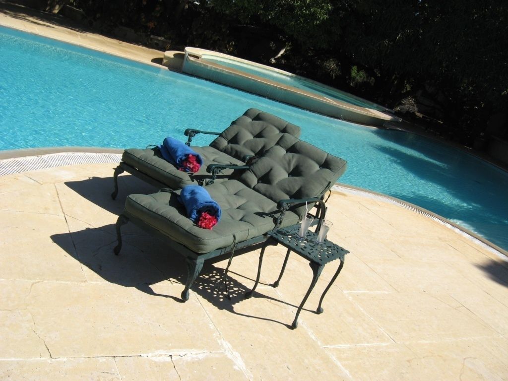 A poolside area with two lounge chairs and a small table, surrounded by a tiled deck.