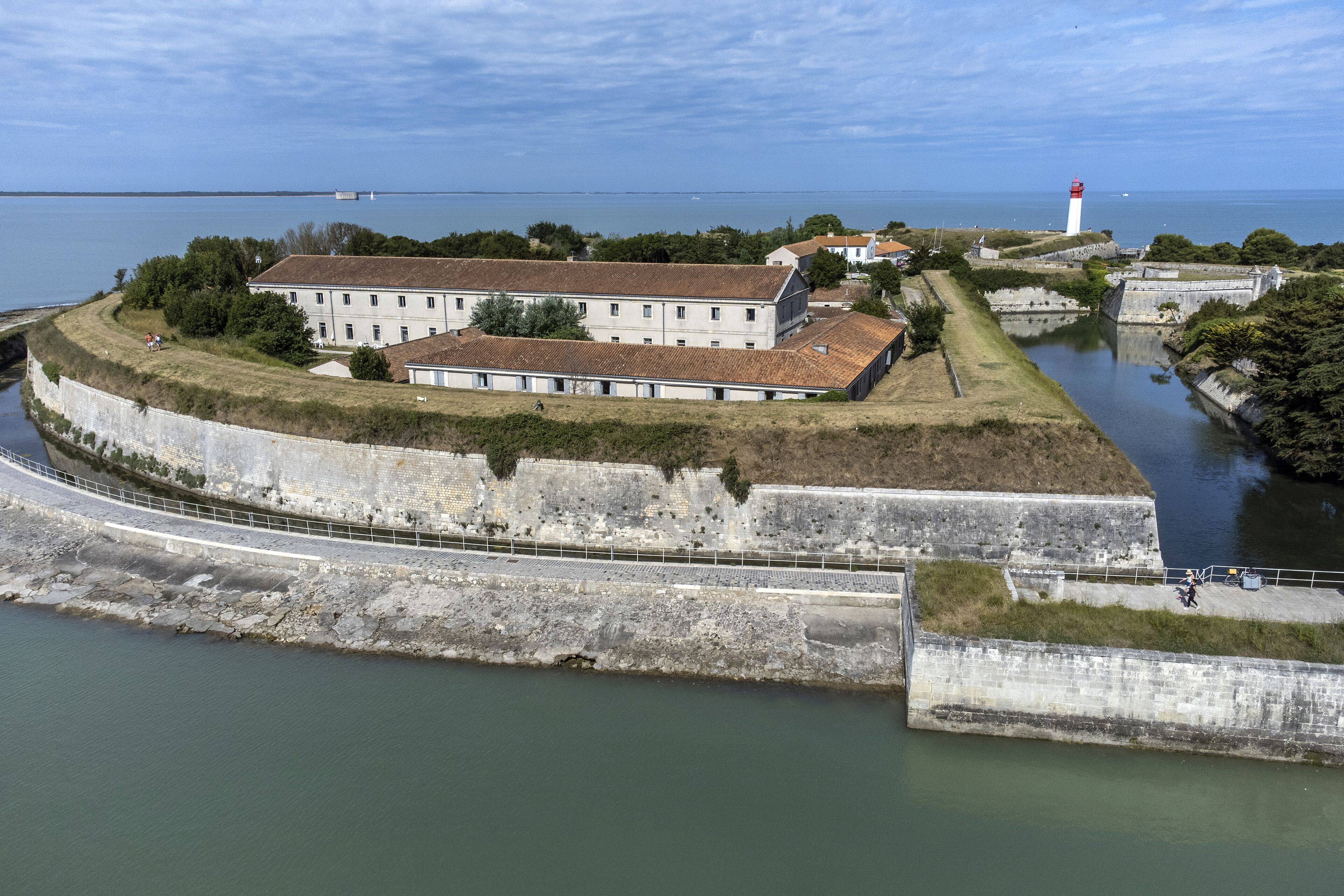 Ein befestigtes Gebäude mit einem großen Innenhof, einem Leuchtturm und einer Wasserfläche.