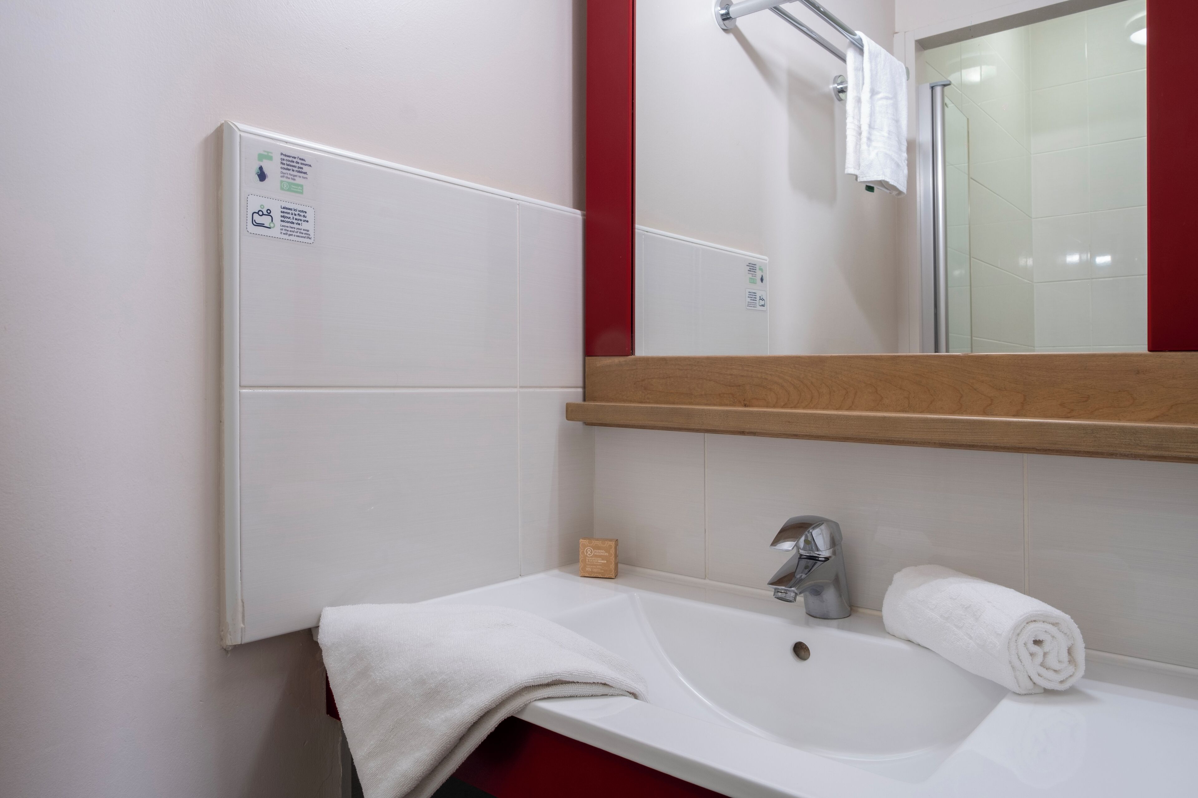 A bathroom with a white sink, a mirror, and a towel rack.