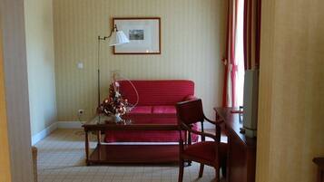 A living room with a red sofa, a wooden coffee table, a chair, a lamp, and a framed picture on the wall.
