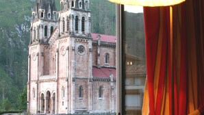 Uma janela com vista para uma igreja histórica com duas torres e um campanário.