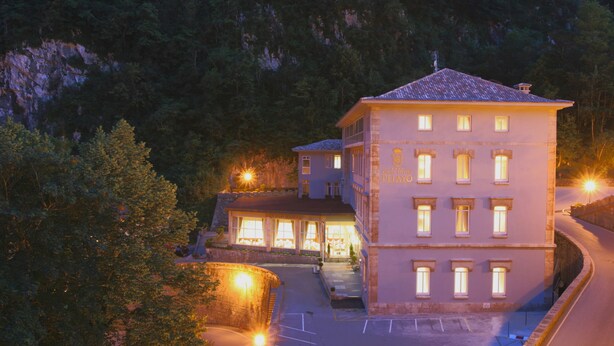 Um hotel grande, com vários andares, entrada imponente e fachada bem iluminada.