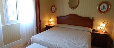 A neatly made bed with a wooden headboard, two bedside tables with lamps, a mirror, and a framed picture on the wall.