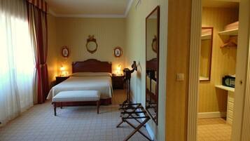 Una habitación de hotel con una cama grande, dos mesitas de noche con lámparas, un espejo y un armario.