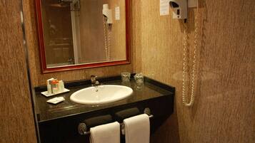 Un bagno con lavandino, specchio, porta asciugamani e asciugacapelli.