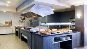 Una mesa de buffet con diversos alimentos y una cocina moderna al fondo.