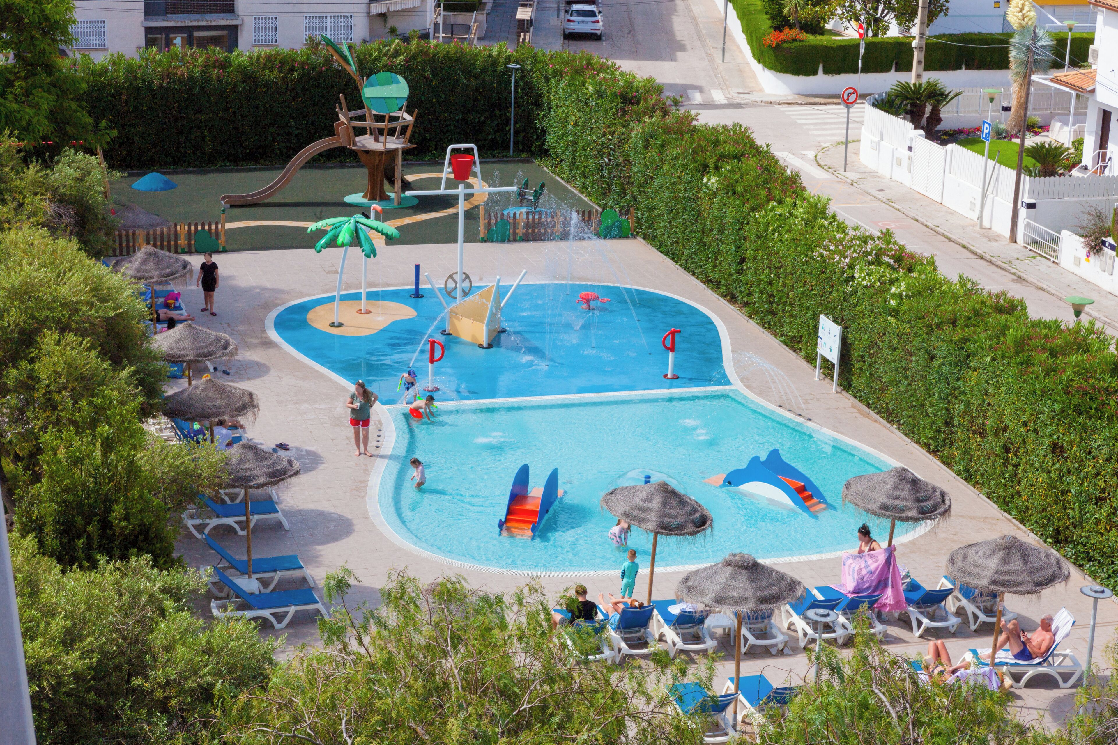 Una piscina con toboganes, sillas de descanso y sombrillas.