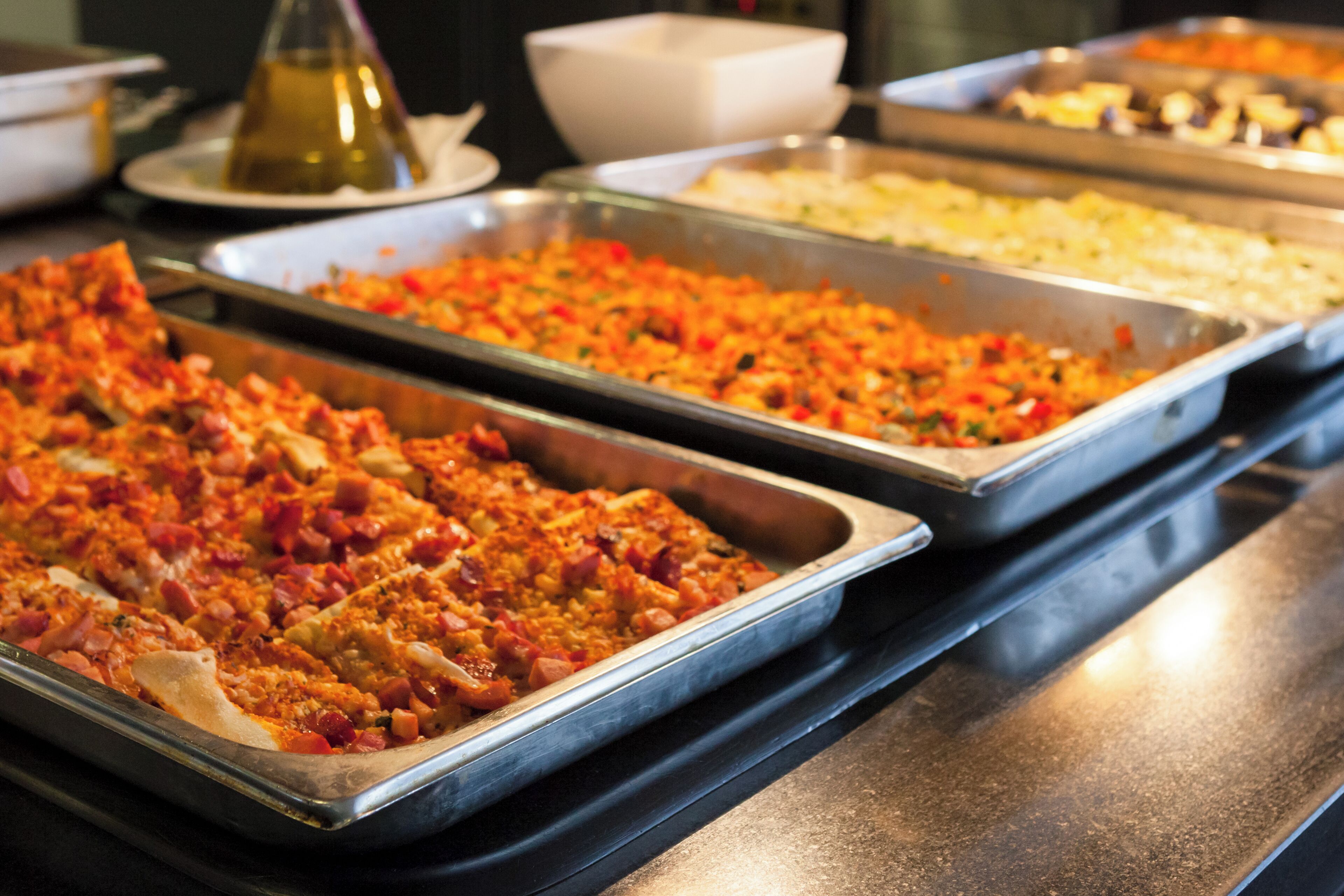 Un bufé con diversos platos, incluyendo una bandeja con un plato rojo y amarillo, un bol blanco y un recipiente con una sustancia amarilla.