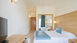 Una habitación de hotel con una cama, un escritorio, una silla, un televisor y un espejo.