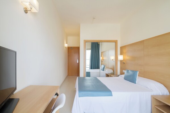 Une chambre d’hôtel avec un lit, un bureau, une chaise, une télévision et un miroir.