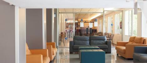 A modern lobby with seating areas, a reception desk, and a glass partition.