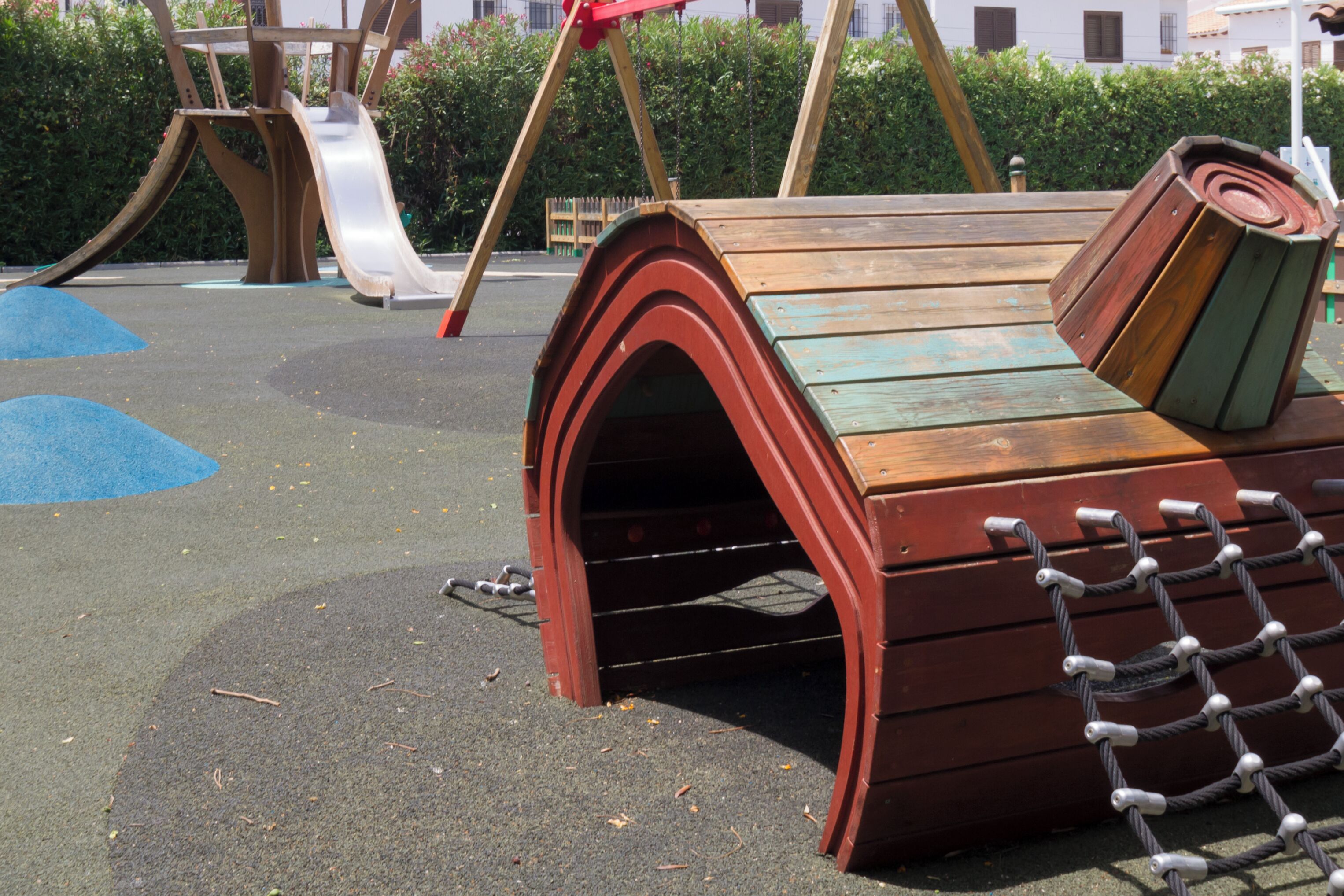 Un parque infantil con una estructura de madera para escalar y un tobogán.