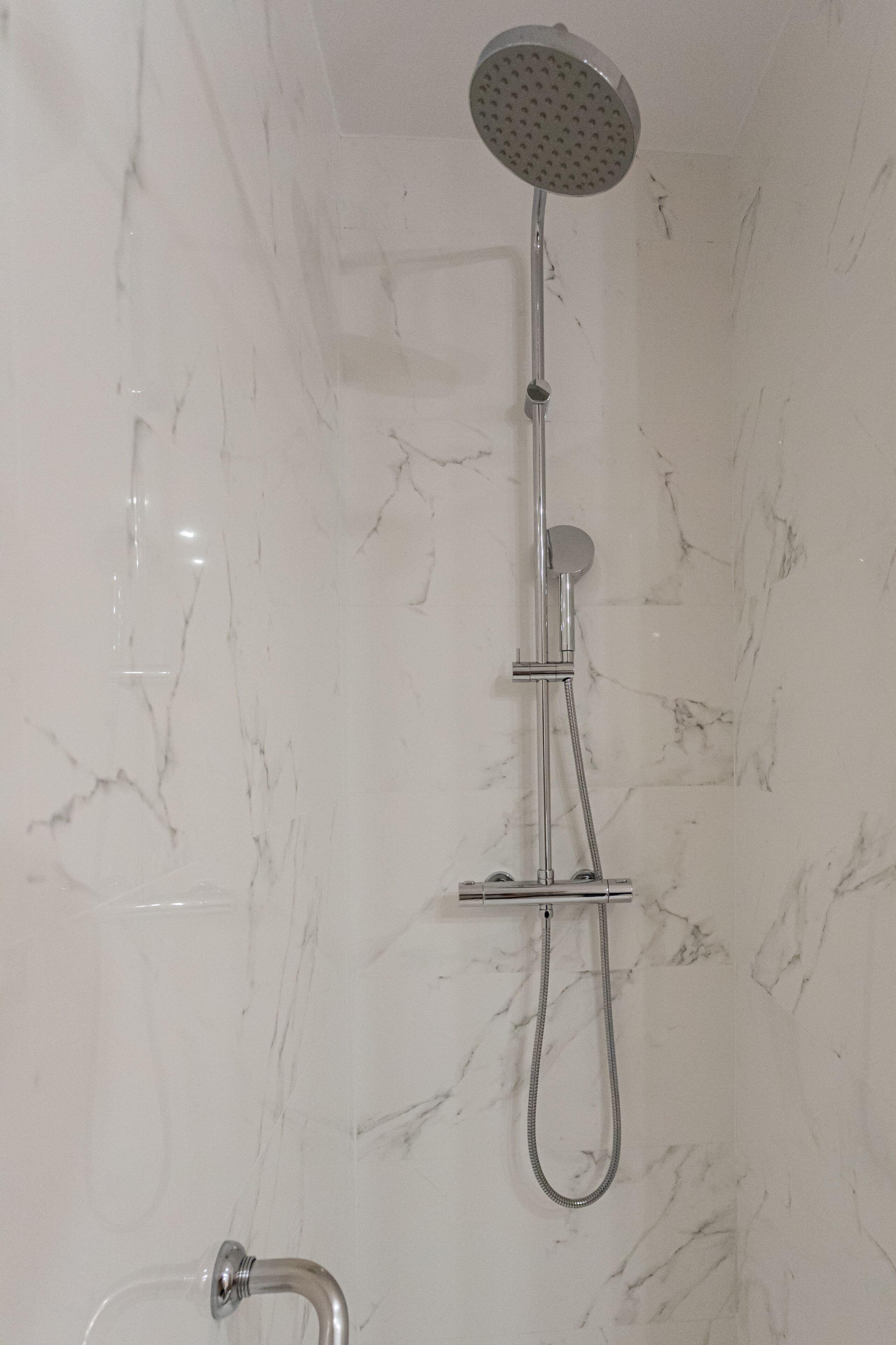A shower with a handheld showerhead and a handheld hose.