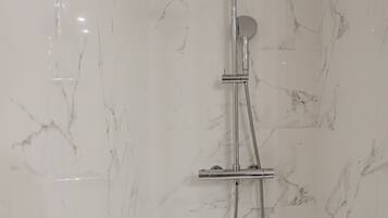 Une douche équipée d’un pommeau de douche à main et d’un flexible à main.