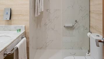 Un baño moderno con lavamanos de mármol, ducha con mampara de vidrio y retrete.