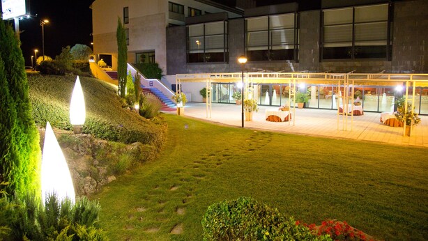 A modern building with a well-lit entrance, a covered outdoor seating area, and a landscaped garden.