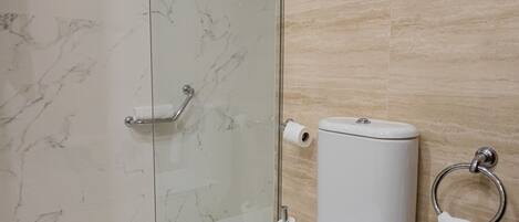 Un baño moderno con ducha de vidrio, inodoro y suelo de mármol.