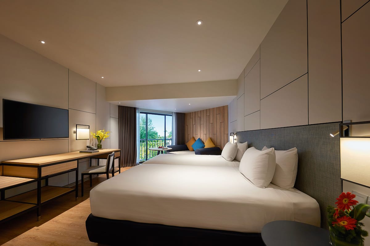 A modern hotel room with a large bed, a desk, a flat-screen TV, and a balcony with a view.