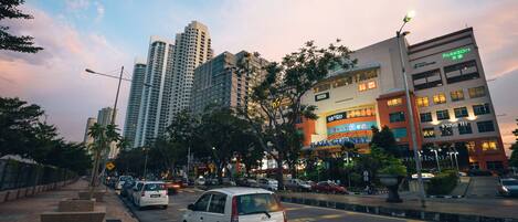 A city street with parked cars, tall buildings, and a mix of commercial and residential structures.