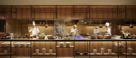 Una cocina moderna con armarios de madera, electrodomésticos de acero inoxidable y chefs preparando comida.