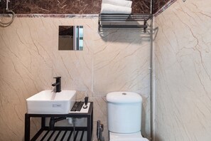 Un baño con un lavamanos blanco, un inodoro y un perchero para toallas.