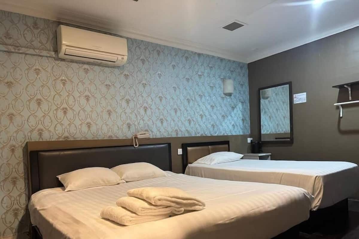 A hotel room with two beds, a large mirror, and an air conditioning unit.