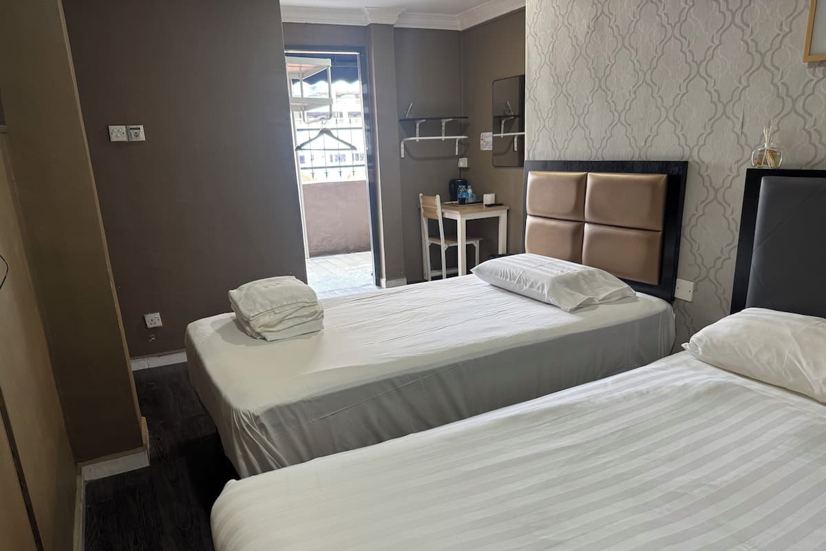 A hotel room with two beds, a small table, and a chair.
