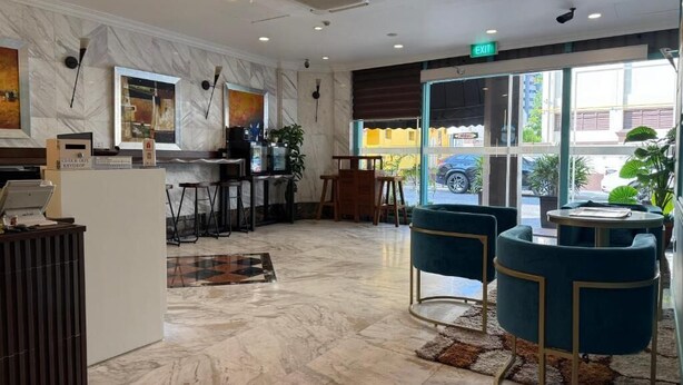Een modern interieur met een receptiebalie, een zithoek en grote ramen met uitzicht op de straat.