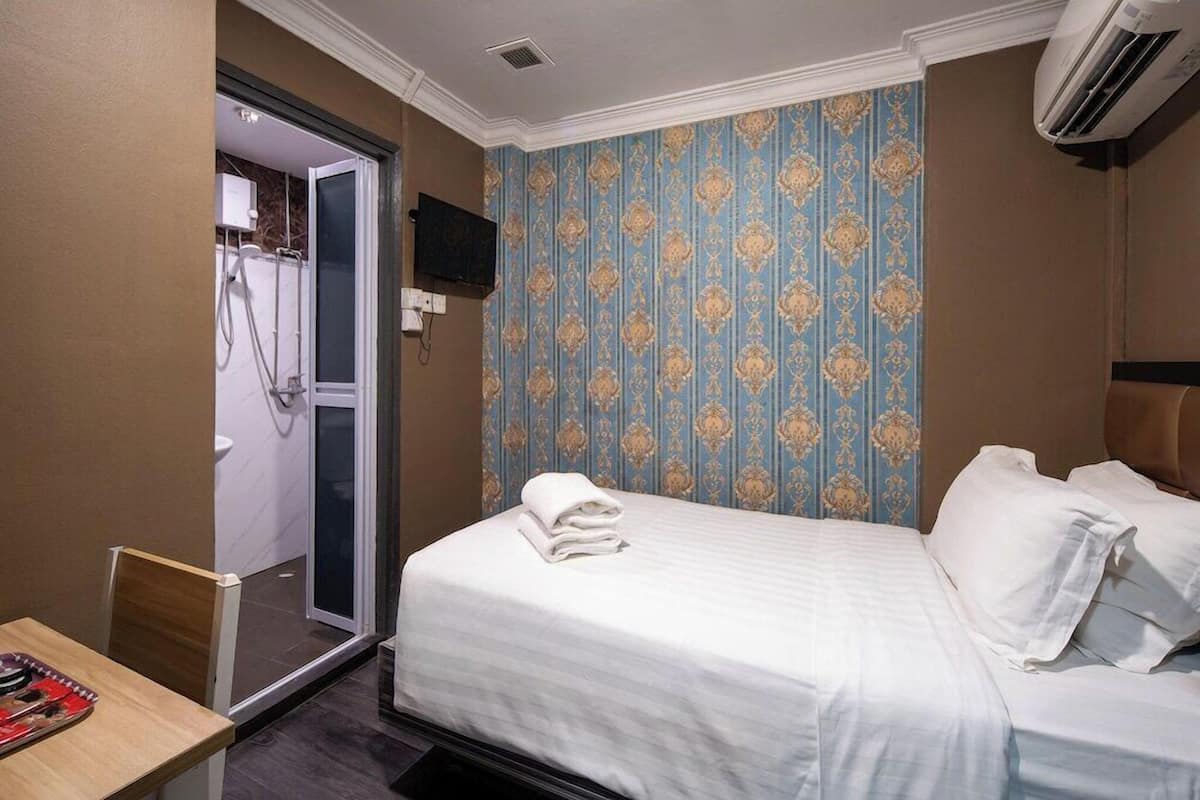 Een hotelkamer met een bed, een bureau, een douche en een televisie.