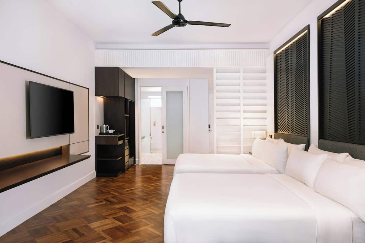Une chambre d’hôtel moderne dotée d’une télévision à écran plat, d’un ventilateur de plafond, d’un canapé et d’un plancher en bois.