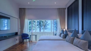 Een moderne hotelkamer met een groot bed, een televisie, een bureau en uitzicht op bomen door het raam.