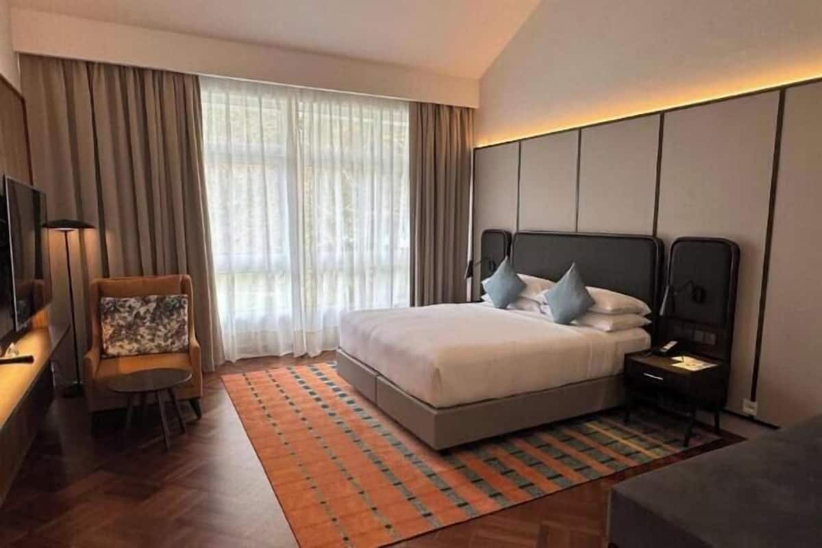 Une chambre d’hôtel avec un lit, une chaise, une télévision et une table de chevet.