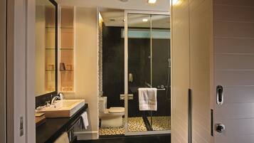 A modern bathroom with a glass shower enclosure, a white sink, and a mirror.
