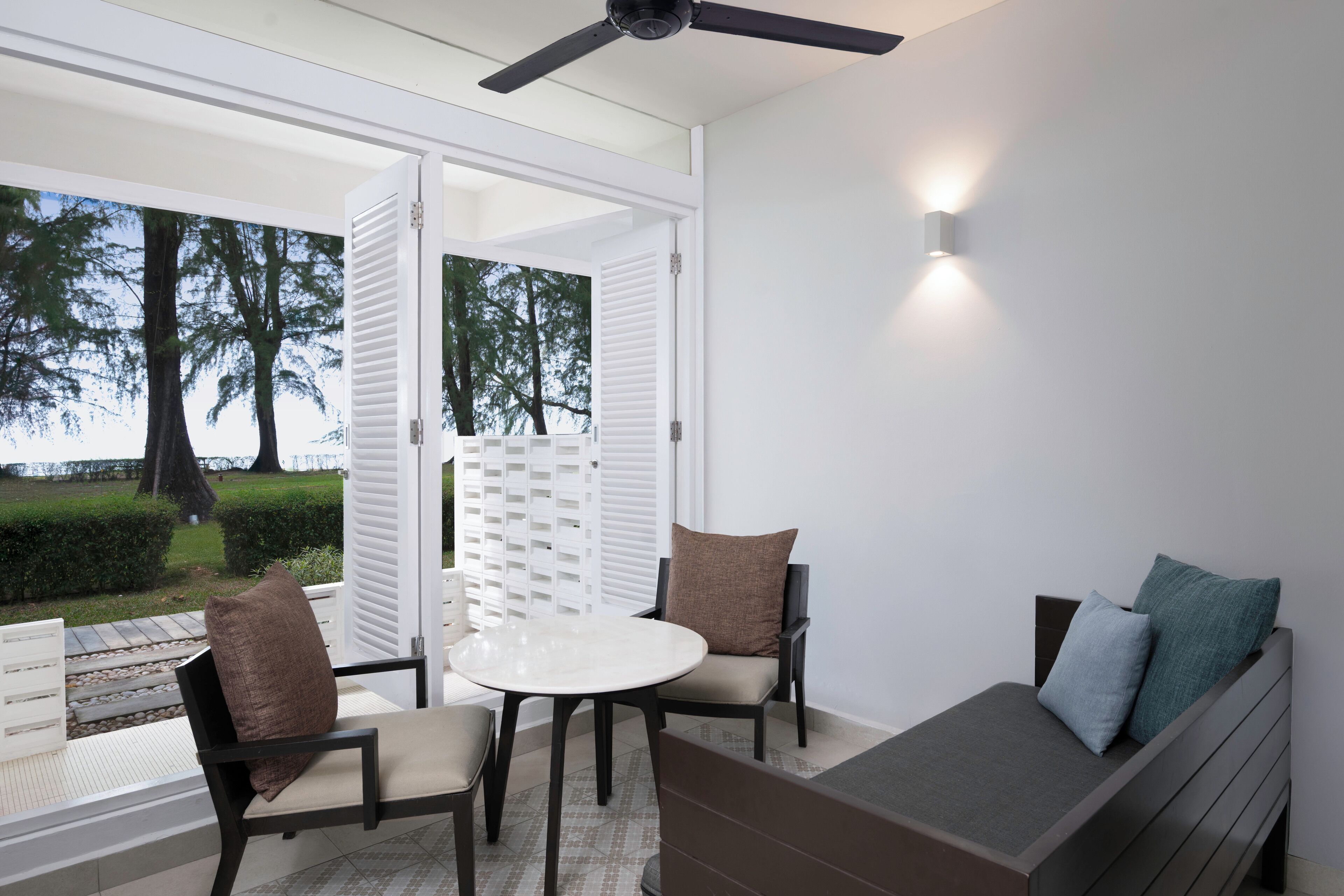 Un espacio al aire libre moderno con una mesa, sillas, un banco y un ventilador de techo.