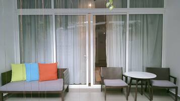 A room with a sofa, two chairs, a table, and a sliding glass door.