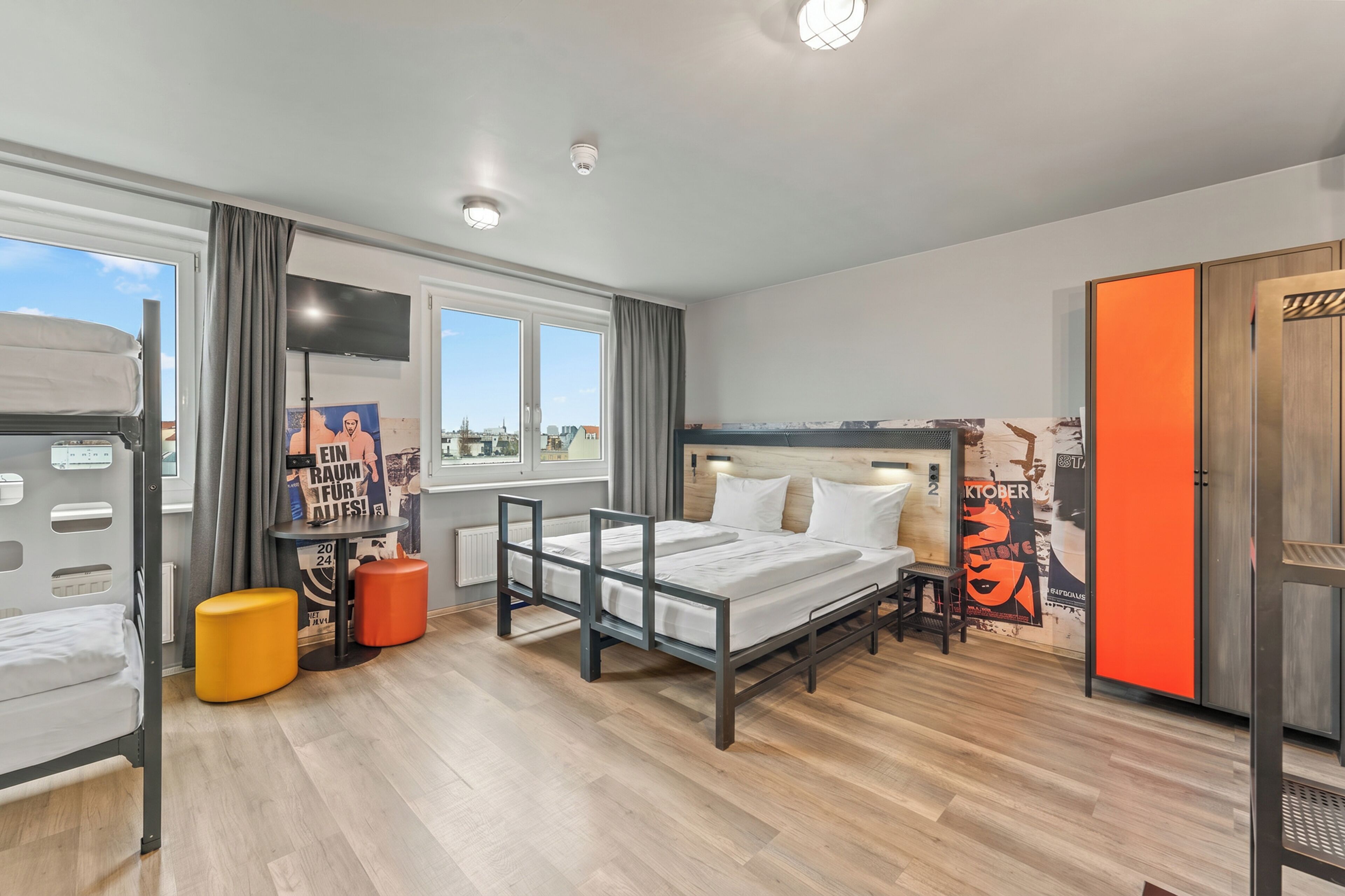 Habitació d'hotel moderna amb llit, escriptori, cadira, finestra i vista a la ciutat.