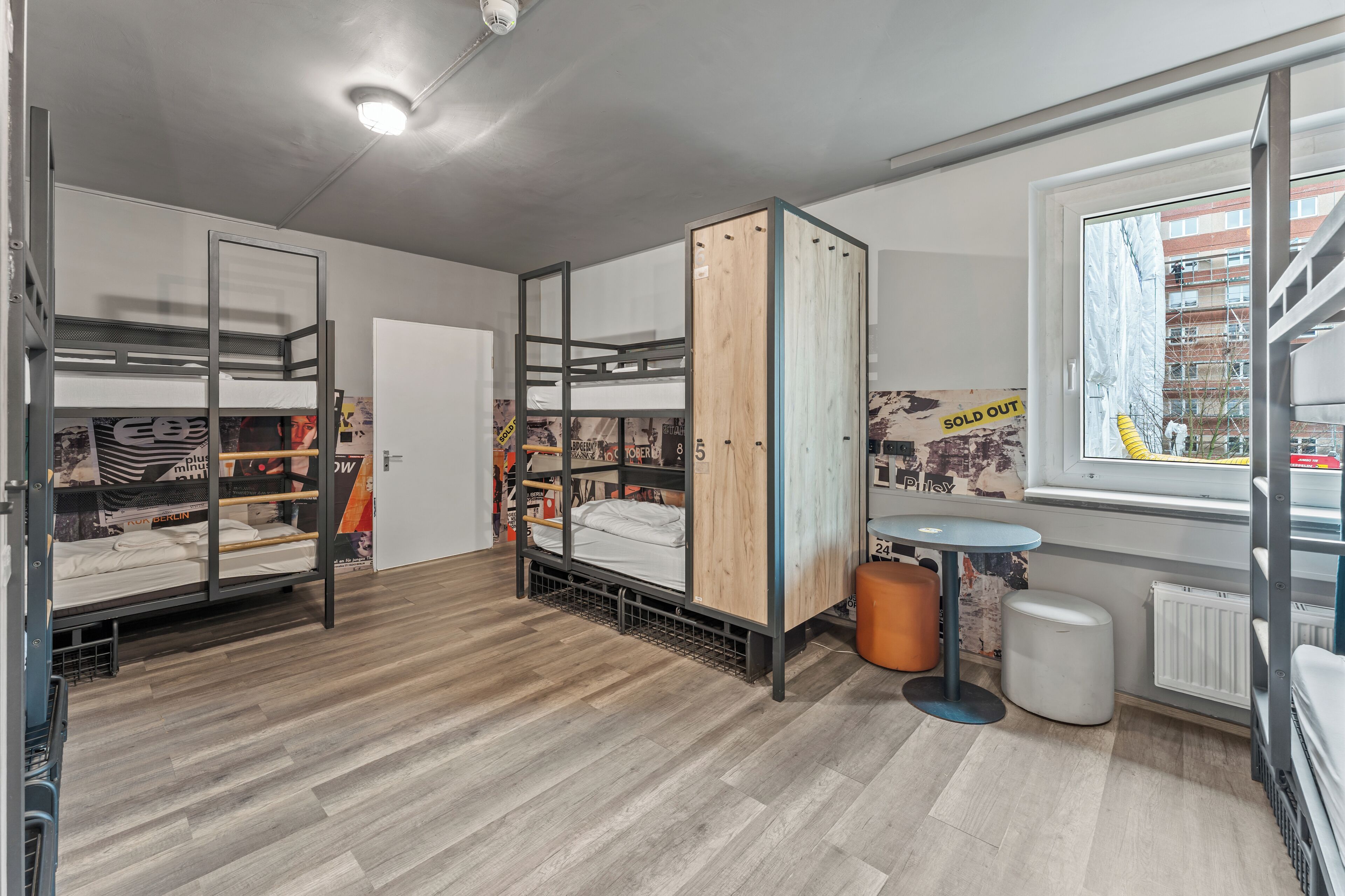 A room with bunk beds, a window with a view, a small table, and a radiator.