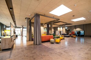 A spacious lobby with a reception desk, seating areas, and a vending machine. - a&o Berlin Mitte (Berlin)
