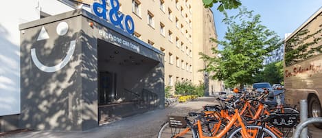 A building with a large 'a&o' sign and a bike rental station with orange bicycles.